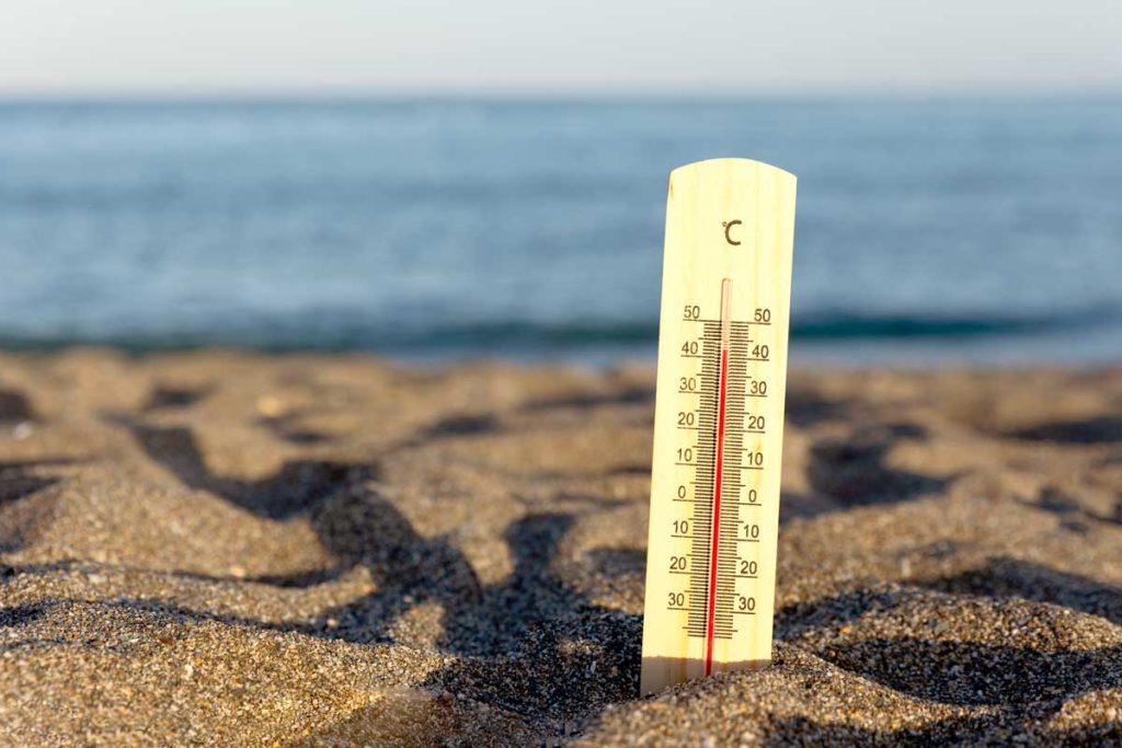 Termómetro con temperatura muy alta incrustado en la arena de la playa